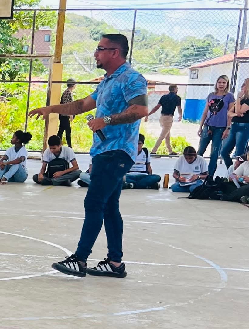 Alisson Oliveira de camisa azul estampada, falando ao microfone